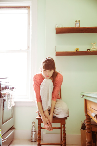 Young Woman Sitting In Kitchen Alone